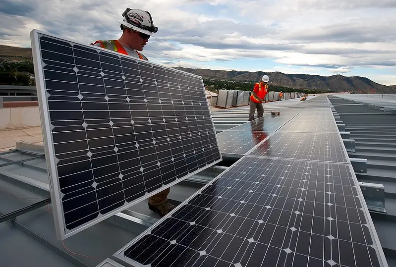 dos instaladores montan placas solares en un tejado de una fábrica 